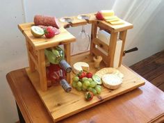 a wooden table with wine glasses, cheese and fruit on it in front of the counter