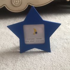 a blue star shaped photo frame sitting on top of a white carpeted floor next to a bed