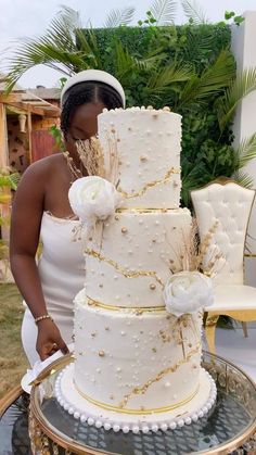 a woman in white dress standing next to a large cake on top of a table