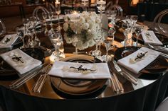 the table is set with black and white linens, silverware, and flowers