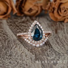 a blue and white diamond ring sitting on top of a wooden table next to roses