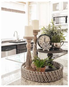 a clock sitting on top of a counter next to a potted plant and candle