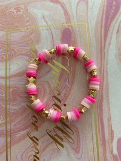 two bracelets with pink and gold beads are on a marble background, one is personalized