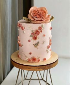 there is a pink cake with flowers on the top and bottom, sitting on a stand