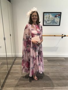 a woman standing in front of a painting wearing a pink dress