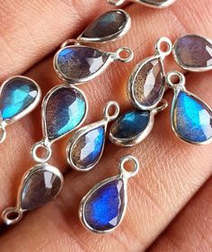 blue and silver tear shaped pendants are shown on someone's hand with their fingers