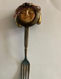 a fork with a face on it and a chain hanging from the back of it