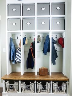 a white coat rack with several bins and clothes hanging on it's sides