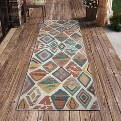 a multicolored area rug on a wooden deck with potted plants in the background