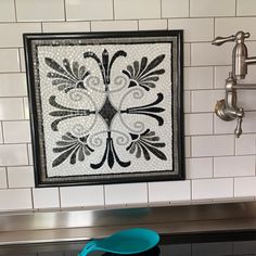 a black and white tile design on the wall above a blue bowl in a kitchen