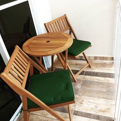 two wooden chairs sitting next to a small table on top of a tile floor near a door