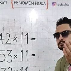 a man wearing sunglasses standing in front of a whiteboard with numbers written on it