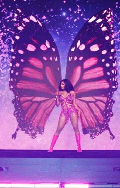 a woman standing on top of a stage in front of a butterfly