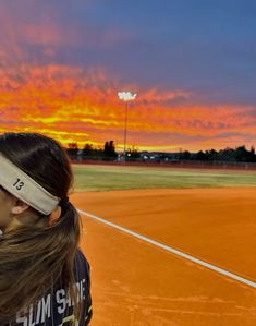 a woman is standing on a tennis court at sunset