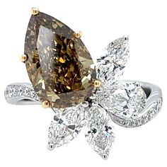 Unveil Elegance with a 3.12ct Fancy Deep Brown-Yellow Pear Diamond Ring Capture attention with this extraordinary pear-shaped diamond ring. The centerpiece is a captivating 3.12 carat natural fancy deep brown-yellow diamond, certified by the Gemological Institute of America (GIA) for authenticity and quality. Unlike traditional colorless diamonds, this rare gem boasts a rich, warm hue with an enchanting play of light. The VVS2 clarity ensures exceptional brilliance. Surrounding this stunning center stone are 4 pear and marquise shaped melee diamonds totaling 1.20 carats, and additional round melee diamonds adding 0.18 carats of sparkle. The "Very Good" polish and symmetry of the cut in all the diamonds maximize their brilliance and fire. This ring is a true conversation starter, a perfect Luxury Brown Diamond Ring, Pear Diamond Ring, Pear Shaped Diamond Ring, Pear Diamond Rings, Colorless Diamond, Rare Gems, Deep Brown, Pear Diamond, Pear Shaped Diamond