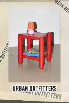 a small red table with a lamp on top and an advertisement for urban outfitters