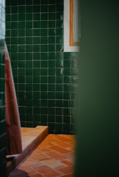 a green tiled bathroom with a wooden bench