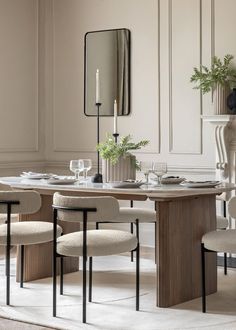 a dining room table with chairs and a mirror on the wall