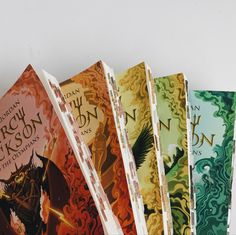 five books lined up on top of each other in front of a white wall with an image of a dragon