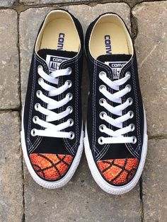 a pair of black sneakers with an orange basketball painted on the side and white laces