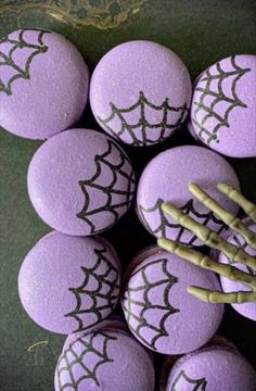 purple halloween macaroons with green stems and spider webs on them, arranged in a circle