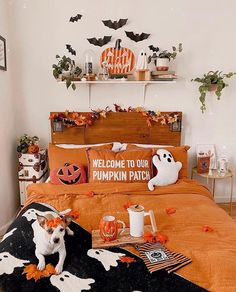 a dog sitting on top of a bed in a room decorated for halloween with pumpkins and ghost decorations