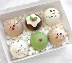 a box filled with assorted decorated donuts on top of white rocks and pebbles