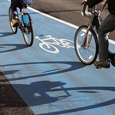 two bicyclists are riding down the bike path