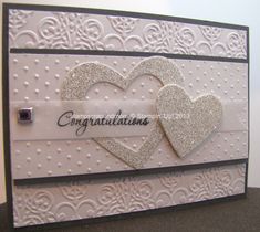 a white card with two hearts and congratulations written on the front in silver glitters