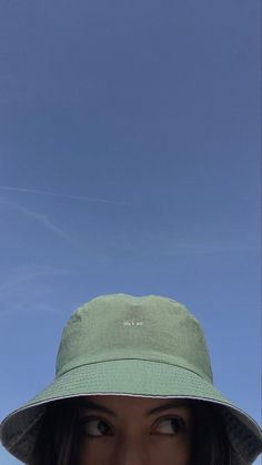 a woman wearing a green hat looking at the camera with a clear blue sky in the background