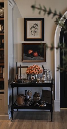 a black table topped with glasses next to a shelf filled with bottles and bowls on top of it