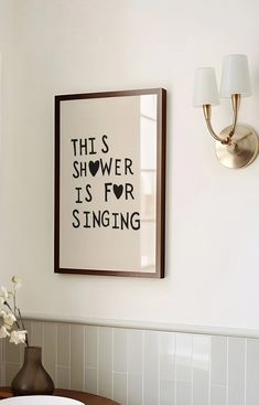 a bathroom with a sink, mirror and framed art on the wall above it that says'this shower is for singing '