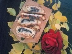 some food is laying on a cutting board next to a red rose and yellow leaves