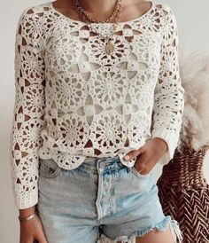 a woman wearing shorts and a white top with crocheted lace on it, standing in front of a wicker basket