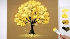 someone is painting a tree with yellow leaves