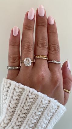 a woman's hand with three different rings on her fingers and one is wearing a sweater