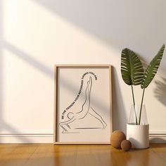 a plant in a white vase next to a framed poster