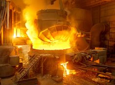 a large metal furnace with yellow flames coming out of it's burners in a factory