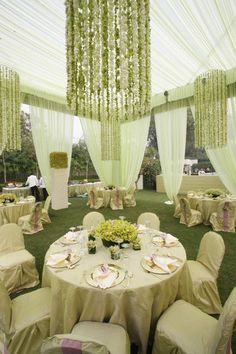 the tables are set up with white linens and green draping on them