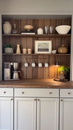 a kitchen with white cabinets and wooden shelves