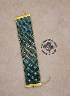 a green beaded bracelet on a white surface with a gold chain attached to it