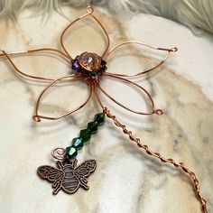 a dragonfly brooch sits on top of a white cloth covered bed with beads and chains