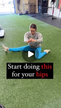 a woman sitting on the ground with her legs crossed and holding a yoga mat in front of her