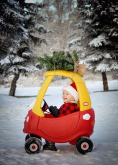 a small child in a red car with a christmas tree on it's roof