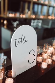 a table with candles and a sign that says table 3 in black writing on it