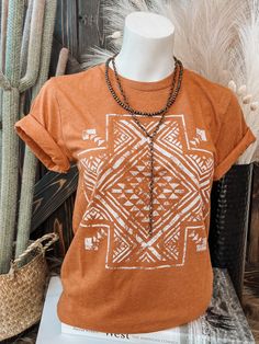 Fun aztec cross graphic in a stunning heathered rust tee! Crew Neck | Short Sleeve | Unisex Fit Material: 50% Polyester | 25% Cotton | 25% Rayon Small (2/4) | Medium (6/8) | Large (10/12) | XL (14/16) | 2XL (18/20) Bohemian Brown Crew Neck T-shirt, Brown Bohemian Crew Neck T-shirt, Bohemian Brown Top With Graphic Print, Cowgirl Grunge, Summer Rodeo, T Shirt Stencils, Clothing Capsule, Aztec Shirt, Cross Graphic