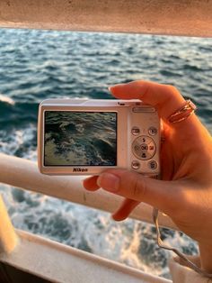 a person is holding up a camera to take a photo on the deck of a boat