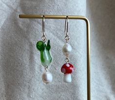 Need a cute and novel cottage core gift for a friend? look no further! These are a lovely mismatched pair of earrings. They will sure to turn heads and are a statement with any outfit.  It's the best of both my favorite beads: mushroom and bok choy goodness. The mushroom and vegetable are made of Lampwork glass beads, chunky freshwater baroque pearls These cute lil boho dangle earrings are sure to please! Handmade Charming Earrings For Gift, Charming Handmade Earrings For Gift, Whimsical Green Mushroom Design Earrings, Unique Mushroom Design Earrings For Gift, Mushroom Earrings Beads, Handmade Fairycore Drop Earrings, Unique Mushroom Design Earrings As Gift, Mushroom Design Dangle Earrings For Gift, Mushroom Design Dangle Earrings As Gift