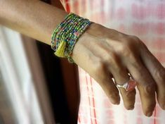 a close up of a person's arm wearing bracelets and rings with beads