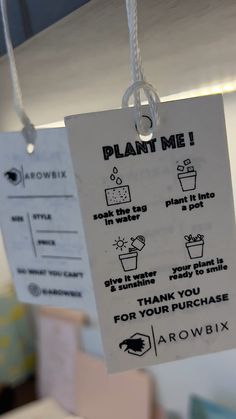 a plant me sign hanging from a ceiling in a store or office area with instructions on how to use it